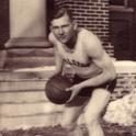 Nordly lunges holding a basketball in front of Sayles-Hill Campus Center