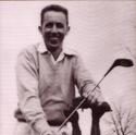 Ulrich, smiling, poses with a caddy of golf clubs