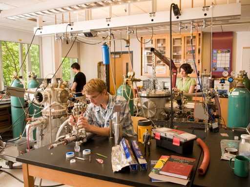 Two students and a professor work in a campus physics lab