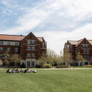 students seated in a circle on the grass outside dorm hall