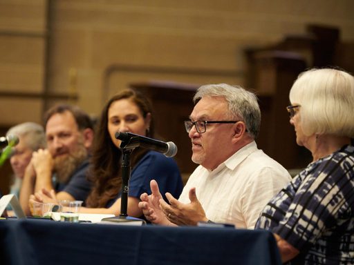 Panelists speak from a table at a panel discussion