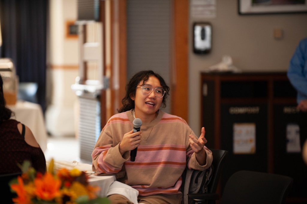 A seated girl speaks into a microphone.