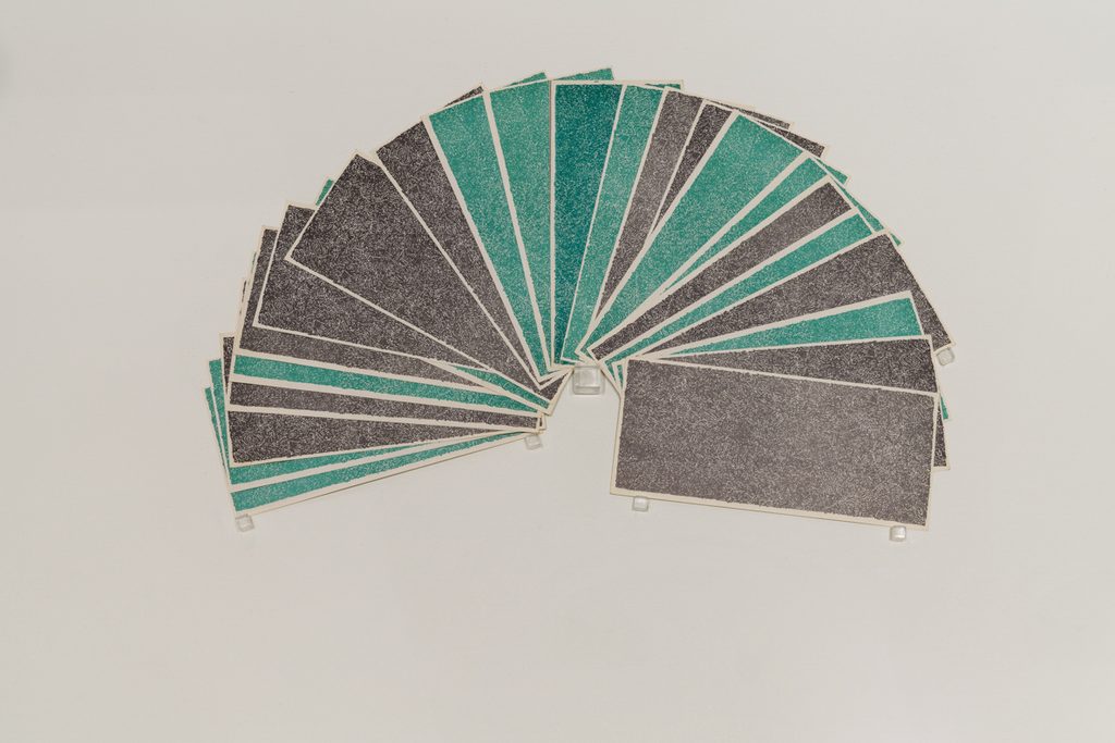 A collection of green and black printed bills are spread out in a fan shape and sit on top of a white background.