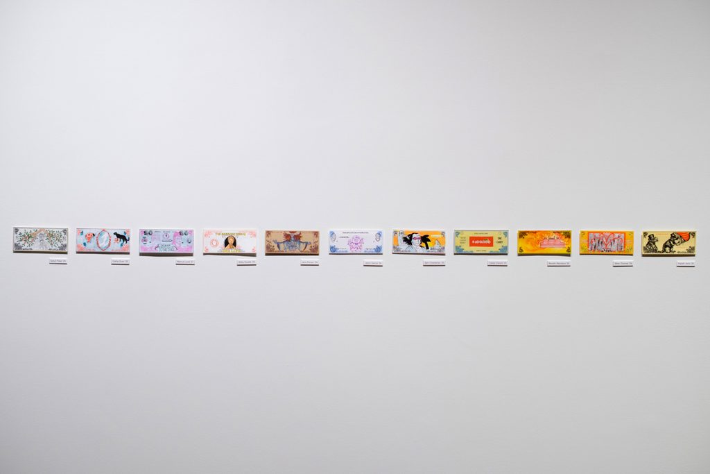 Brightly colored, student created bills are mounted in a single row along the wall.