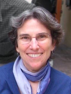 women wearing glasses and a purple scarf smiles into the camera