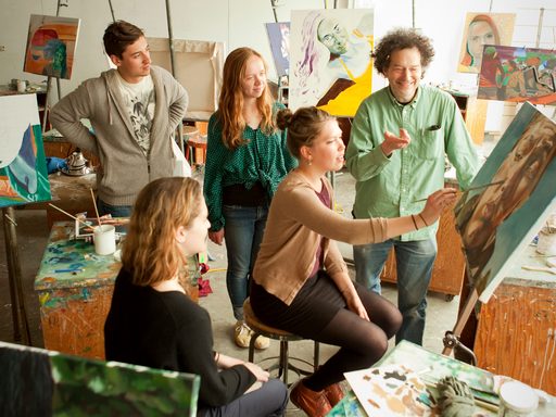 A professor and students examine a student's painting in progress