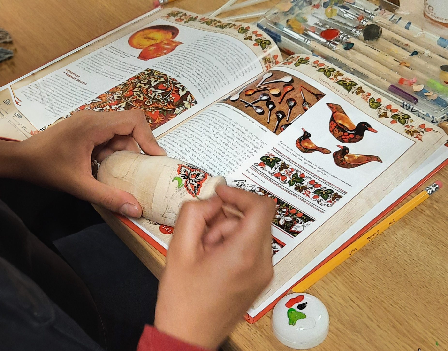 hands making matrioshkas over a detailed instructional book