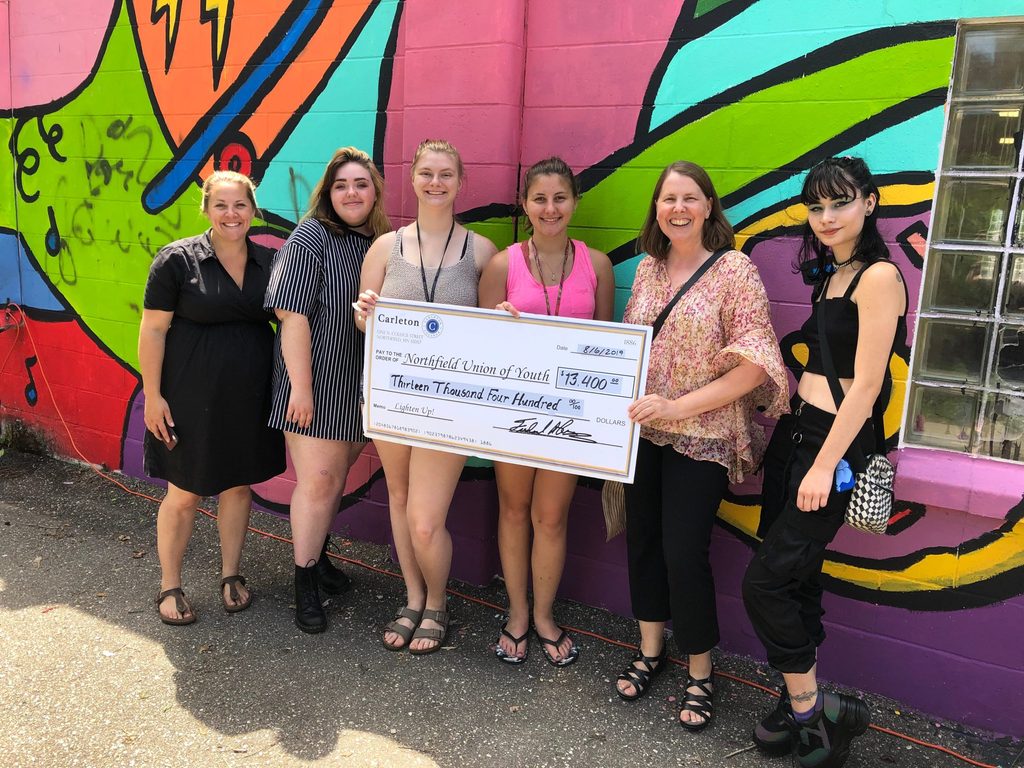 Erika Zweifel presents a giant check to the Northfield Union of Youth