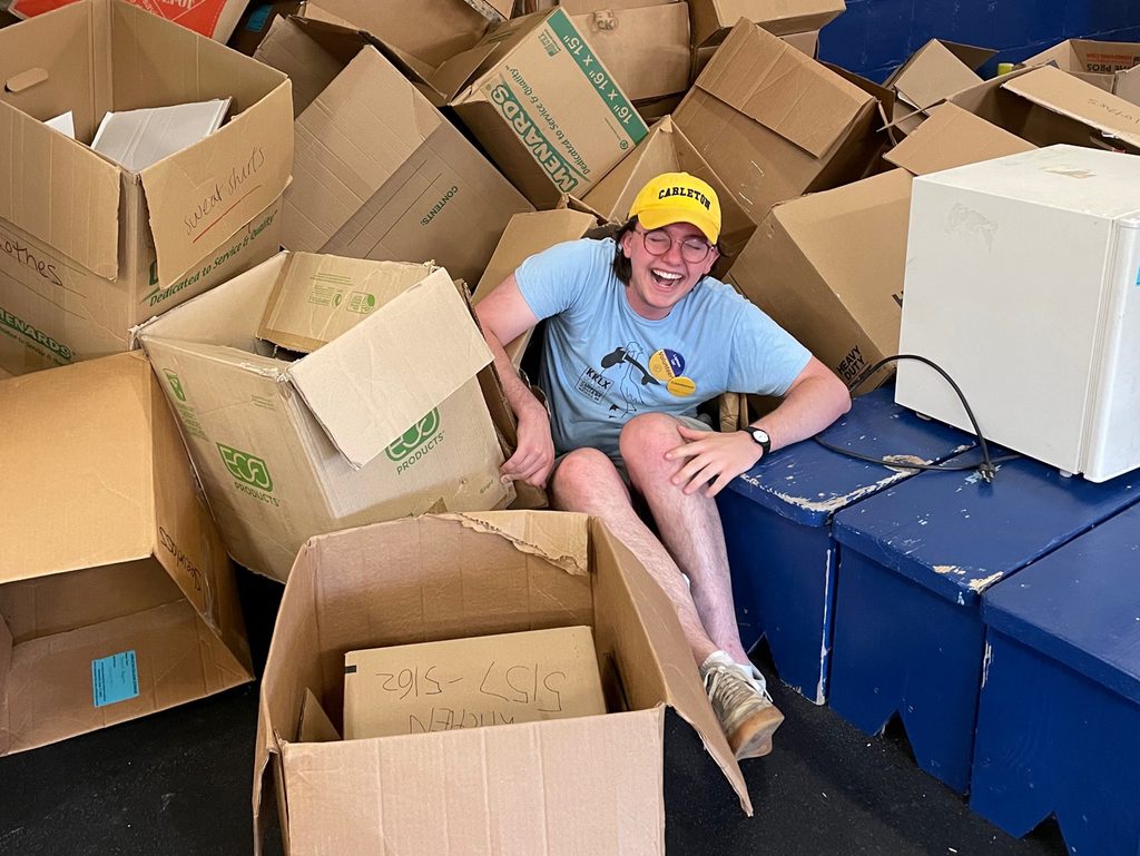 Jack Rizzo '24 sits in a pile of empty cardboard boxes, laughing