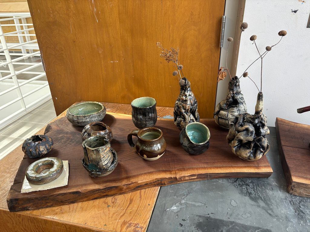 A series of ceramic sculptures on a workbench in a studio