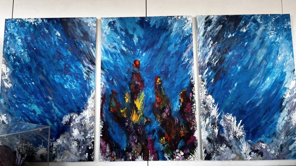 Three-panel painting of a colorful coral reef in a blue ocean