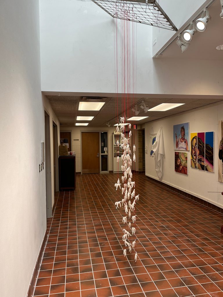 Sculpture of porcelain horses suspended from red cord