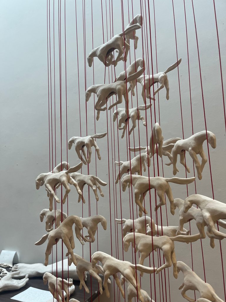 Sculpture of porcelain horses suspended from red cord