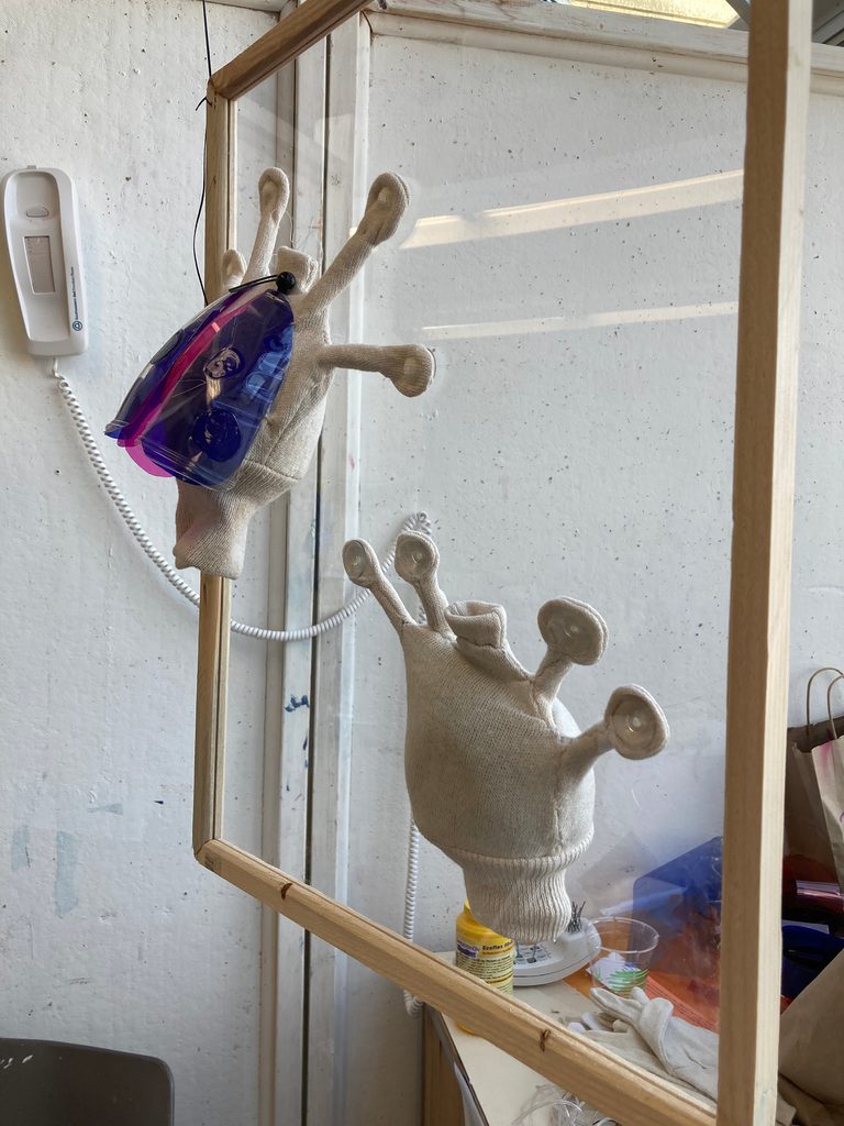 Abstract sculptural installation with gloves, reused plastic food containers, lighting gel offcuts, wood, and clear acrylic
