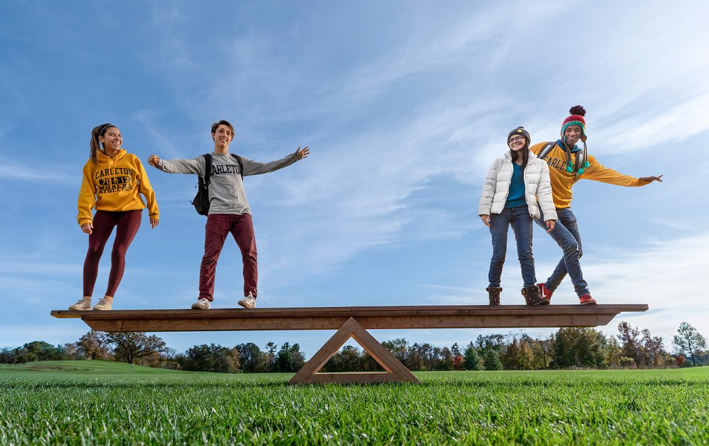 Four students balance on a gigantic see-saw