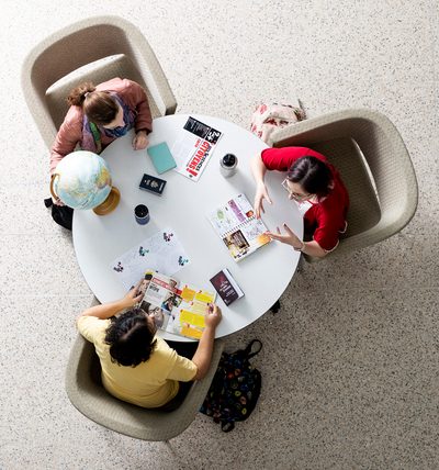 Three students seated at a round table, viewed from overhead
