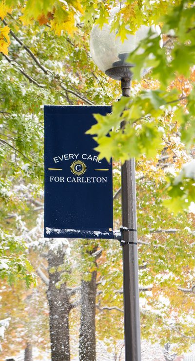 snow falls upon a banner reading "Every Carl for Carleton"