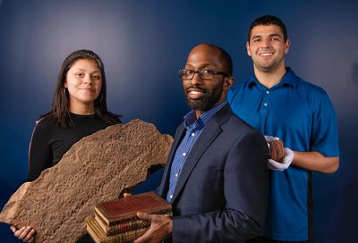 three people smile as they hold objects from their research