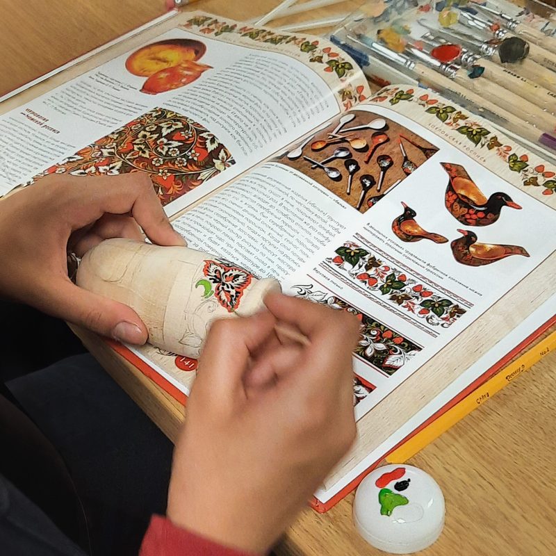 hands making matrioshkas over a detailed instructional book