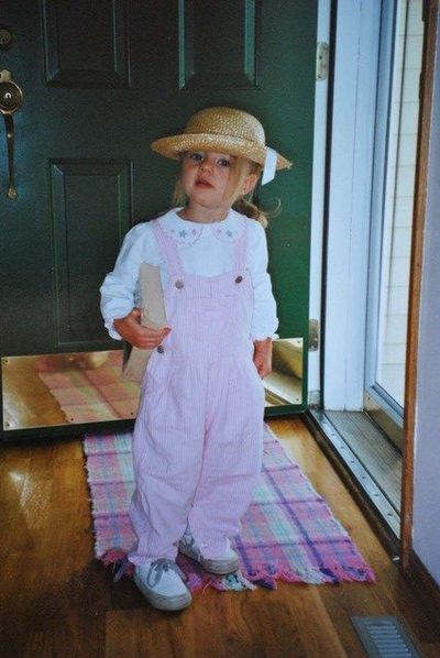 Photo of a young girl holding a book in pink overalls